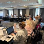 Board meeting participants engaged in discussion and note-taking, with focus on collaboration and strategic planning for Rocky Mountain Commercial Real Estate initiatives.